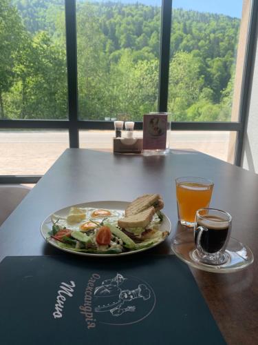 a table with a plate of food and a glass of orange juice at Карпатський Готель Олександрія in Mykulychyn