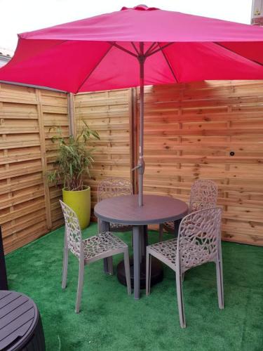 居讓梅斯特拉的住宿－Studio avec mezzanine，一张桌子和椅子,配有红色雨伞