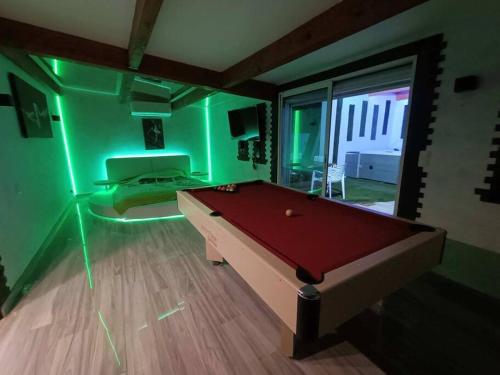 Zimmer mit Billardtisch in einem Zimmer mit grüner Beleuchtung in der Unterkunft Appartement Le Secret Spa billard sensualité in Espondeilhan