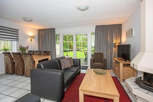 a living room with a couch and a television and a table at Bungalow - 6 Persons in Hellendoorn