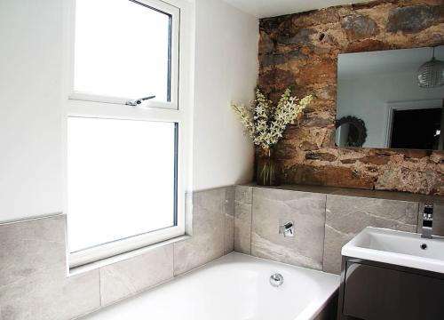 uma casa de banho com um lavatório, uma janela e um espelho. em Sommersway Cottage em Torquay