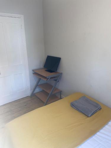 a room with a bed and a desk with a laptop at Modernified Properties in Canterbury