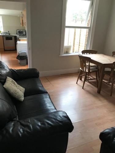 ein Wohnzimmer mit einem schwarzen Ledersofa und einem Tisch in der Unterkunft Modernified Properties in Canterbury