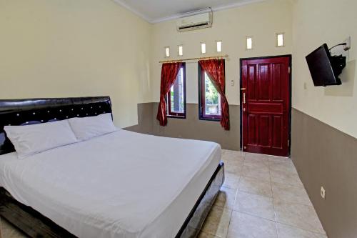 1 dormitorio con 1 cama y puerta roja en OYO 92624 Stone Homestay, en Tjakranegara