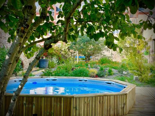 una bañera de hidromasaje en un jardín con un árbol en Coté jardin en Sainte-Suzanne
