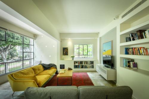 salon z żółtą kanapą i stołem w obiekcie Spacious & Green 3BR Apt w Balcony in City Center by Sea N' Rent w Tel Awiwie