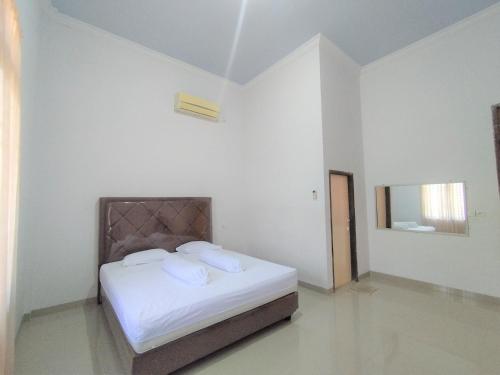 a bedroom with a bed with white sheets and a mirror at OYO Life 92637 Kost Arya Exclusive in Jambi