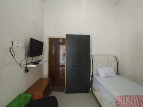 Dormitorio pequeño con cama y TV en OYO Life 92637 Kost Arya Exclusive en Jambi