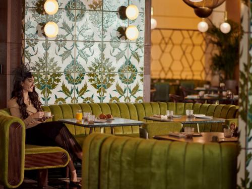 a woman sitting at a table in a restaurant at Grand Hyatt Kuwait in Kuwait