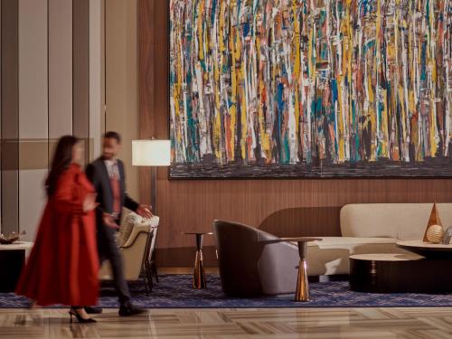 a man and woman walking through a lobby with a painting at Grand Hyatt Kuwait in Kuwait