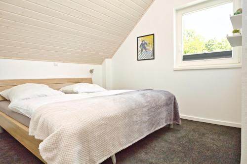 a bedroom with a bed and a window at Blinkfüer - a88738 in Nordhorn