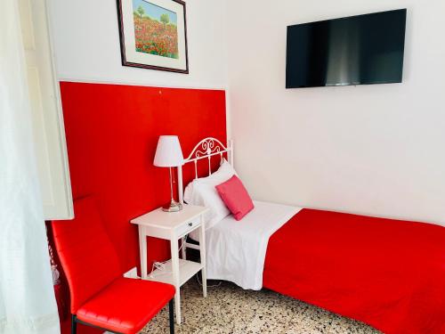 1 dormitorio rojo y blanco con 1 cama y 1 silla en Casa Verga, en Siracusa