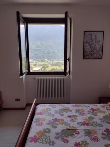 ein Schlafzimmer mit einem Bett und einem großen Fenster in der Unterkunft Appartamento vacanza il Picchio Rosso in Mantello