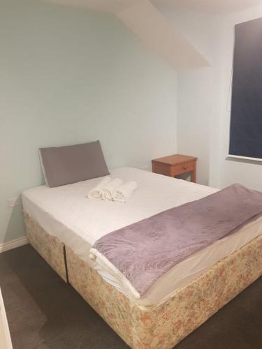 een slaapkamer met een groot bed en een paarse deken bij Big ensuite bed room in a modern town house in Coundon