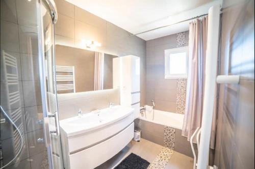 y baño con bañera, lavabo y espejo. en VILLA FLAVIE- luxueuse - Confort Jardin Barcecue 10min PLAGE- FAMILLE-PISCINE-TOP PROS SERVICES Conciergerie en Lattes