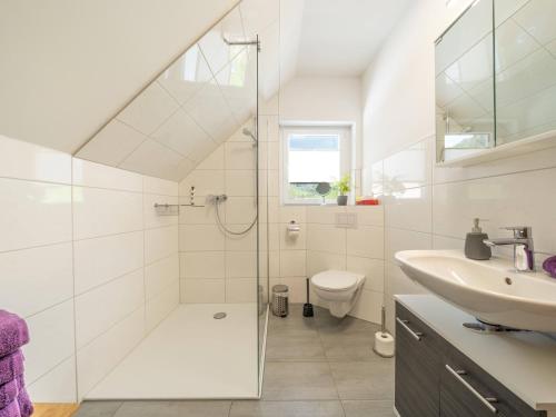 a white bathroom with a shower and a sink at Ferienwohnung am Spielberg in Freiamt