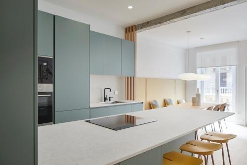 a kitchen with blue cabinets and a counter with stools at Daira Arena by FeelFree Rentals in San Sebastián