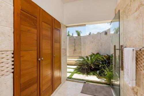 a large wooden door in a bathroom with a garden at LAS CANAS 20 POOL JACUZZI GAMES HIBACHi STAFF in La Romana