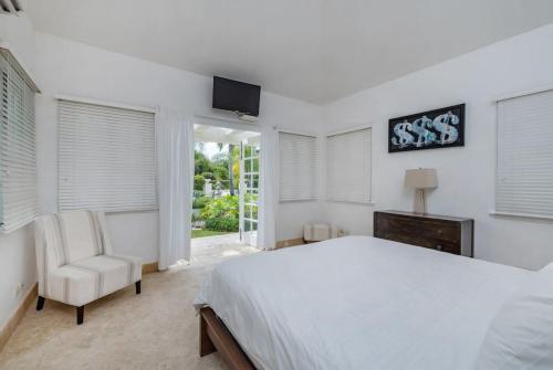 een witte slaapkamer met een bed en een stoel bij VILLA BLANCA CHEF BUTLER MAiD POOL JACUZZI NEAR THE BEACH in Punta Cana