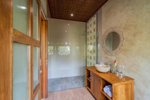 La salle de bains est pourvue d'un lavabo et d'un miroir. dans l'établissement Narada Suite & Villa, à Ubud