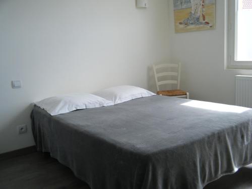 a bedroom with a bed with a gray blanket on it at L'univers in Grand-Fort-Philippe