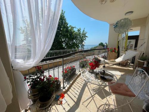 a balcony with flowers and a railing with a window at Thracian Cliffs Private Apartment in Kavarna