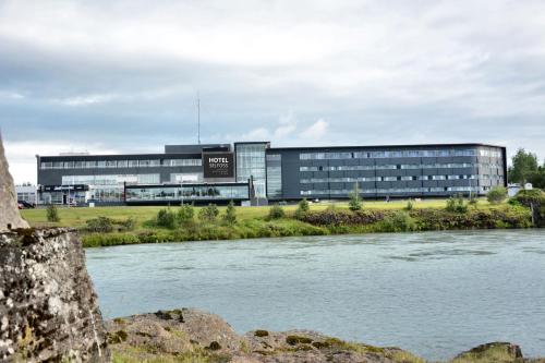 an office building with a river in front of it at Hotel Selfoss in Selfoss