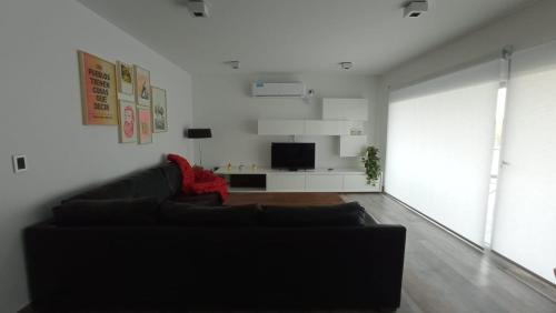 ein Wohnzimmer mit einem schwarzen Sofa und einem TV in der Unterkunft Casa en el mar in Puerto Pirámides
