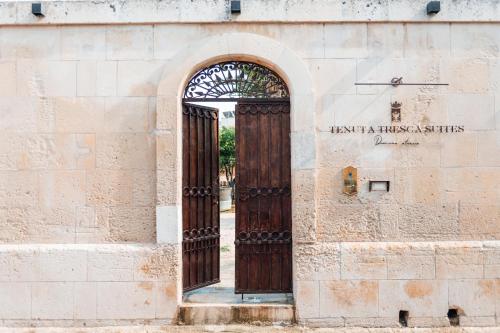 una entrada a un edificio con puerta de madera en Tenuta Tresca Suites - Dimora Storica, en San Cassiano