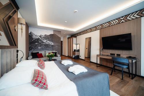 ein Hotelzimmer mit einem großen weißen Bett und einem Schreibtisch in der Unterkunft Rysy Boutique Hotel in Zakopane
