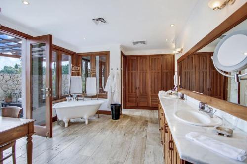 拉羅馬納的住宿－INGENIO 9 TOP RATED VILLA WiTH POOL GOLF CARTS STAFF，大型浴室设有两个盥洗盆和浴缸。