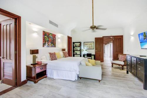 a bedroom with a white bed and a living room at INGENIO 9 TOP RATED VILLA WiTH POOL GOLF CARTS STAFF in La Romana