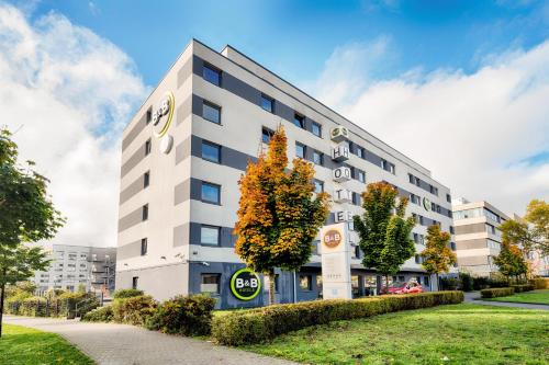 ein weißes Gebäude mit Bäumen davor in der Unterkunft B&B Hotel Wiesbaden in Wiesbaden