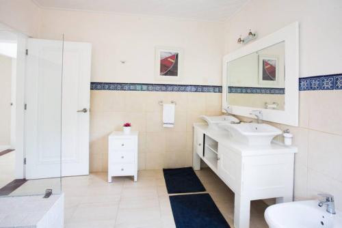 a white bathroom with two sinks and a mirror at TORTUGA B7 GOLF FRONT VILLA WITH POOL CART AND MAiD in Punta Cana