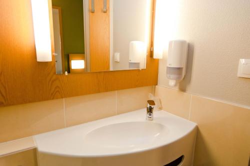 uma casa de banho com um lavatório branco e um espelho. em B&B HOTEL Wrocław Centrum em Breslávia