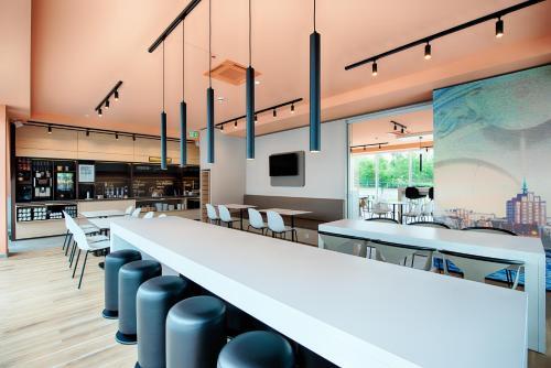 a long white counter in a restaurant with tables and chairs at B&B Hotel Rostock-Hafen in Rostock