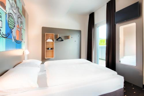 2 camas en un dormitorio con ventana en B&B Hotel Stuttgart-Neckarhafen, en Stuttgart