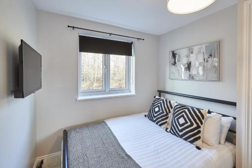 a bedroom with a bed with a television and a window at Vert Vale Apartment in Newcastle upon Tyne