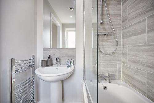 a white bathroom with a sink and a shower at Vert Vale Apartment in Newcastle upon Tyne