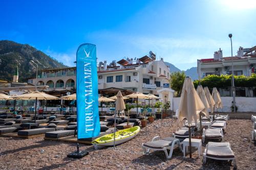un grupo de sillas y sombrillas de playa y un cartel en Hotel Turunç-Malmen, en Turunç