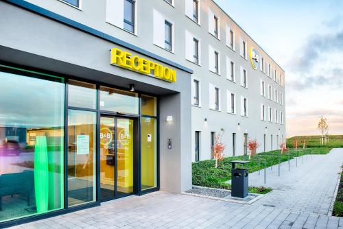 um edifício com um sinal amarelo na frente dele em B&B Hotel Rust-Ettenheim em Ettenheim