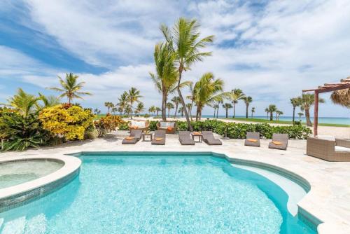 a pool with chairs and palm trees and the ocean at CALETON 8 OCEAN VIEW WITH POOL CHEF BUTLER MAiD EDEN ROC BEACH CLUB ACCESS in Punta Cana