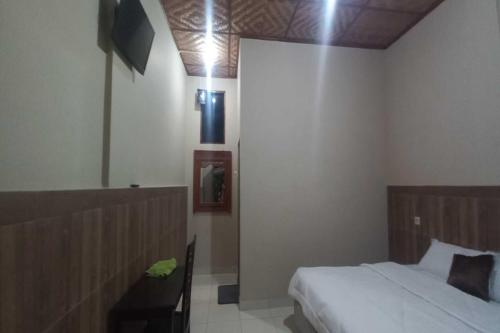 OYO 92628 Raja Alam Homestay في Karanganyar: غرفة نوم مع سرير وتلفزيون على الحائط