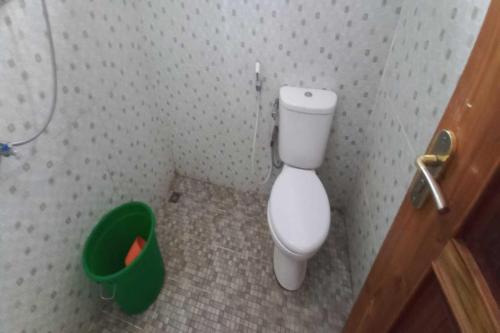 La salle de bains est pourvue de toilettes et d'un seau vert. dans l'établissement OYO 92628 Raja Alam Homestay, à Karanganyar