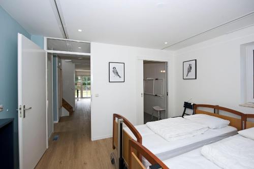 two beds in a room with white walls and wooden floors at Vakantiepark Hellendoorn in Hellendoorn