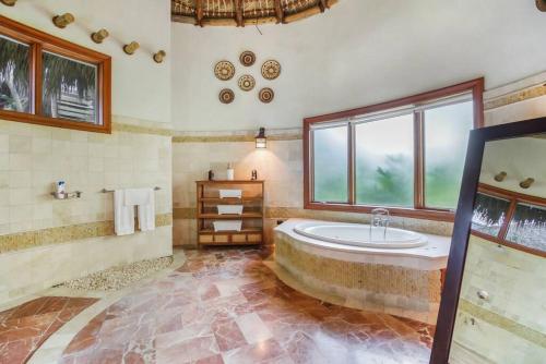 a large bathroom with a tub and a window at Caleton 16 Ocean view 5 bedroom villa with Chef Butler Maid Golf Cart in Punta Cana
