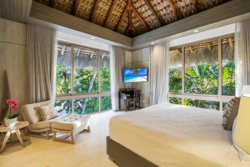 a bedroom with a bed and a tv and windows at Caleton 16 Ocean view 5 bedroom villa with Chef Butler Maid Golf Cart in Punta Cana