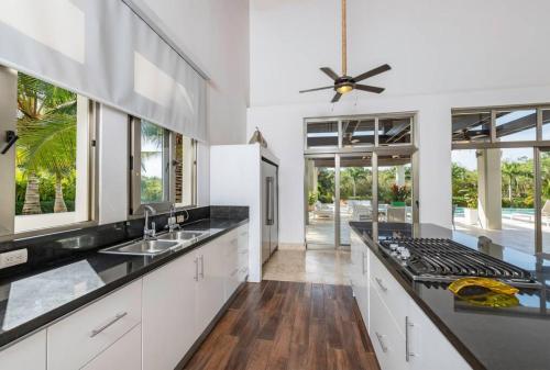 a kitchen with white cabinets and black counter tops at VILLA HERMOSA CHEF MAiD POOL JACUZZI GOLF CART in La Romana