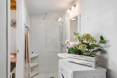 een badkamer met witte muren en een witte wastafel met bloemen bij Arrecife 4 U in Arrecife