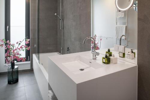 een witte badkamer met een wastafel en een douche bij AMANO HOME Apartments in Berlijn